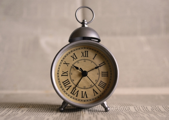 Old fashioned alarm clock on a white table against a white wall