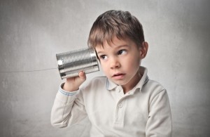 boy with a tin can and piece of string held to his ear